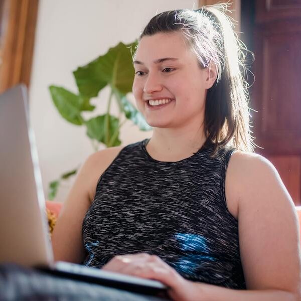 Übergewichtige junge Frau lächelnd am Laptop