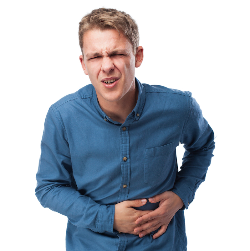 Junger Mann mit schmerzverzerrtem Gesicht hält sich den Bauch